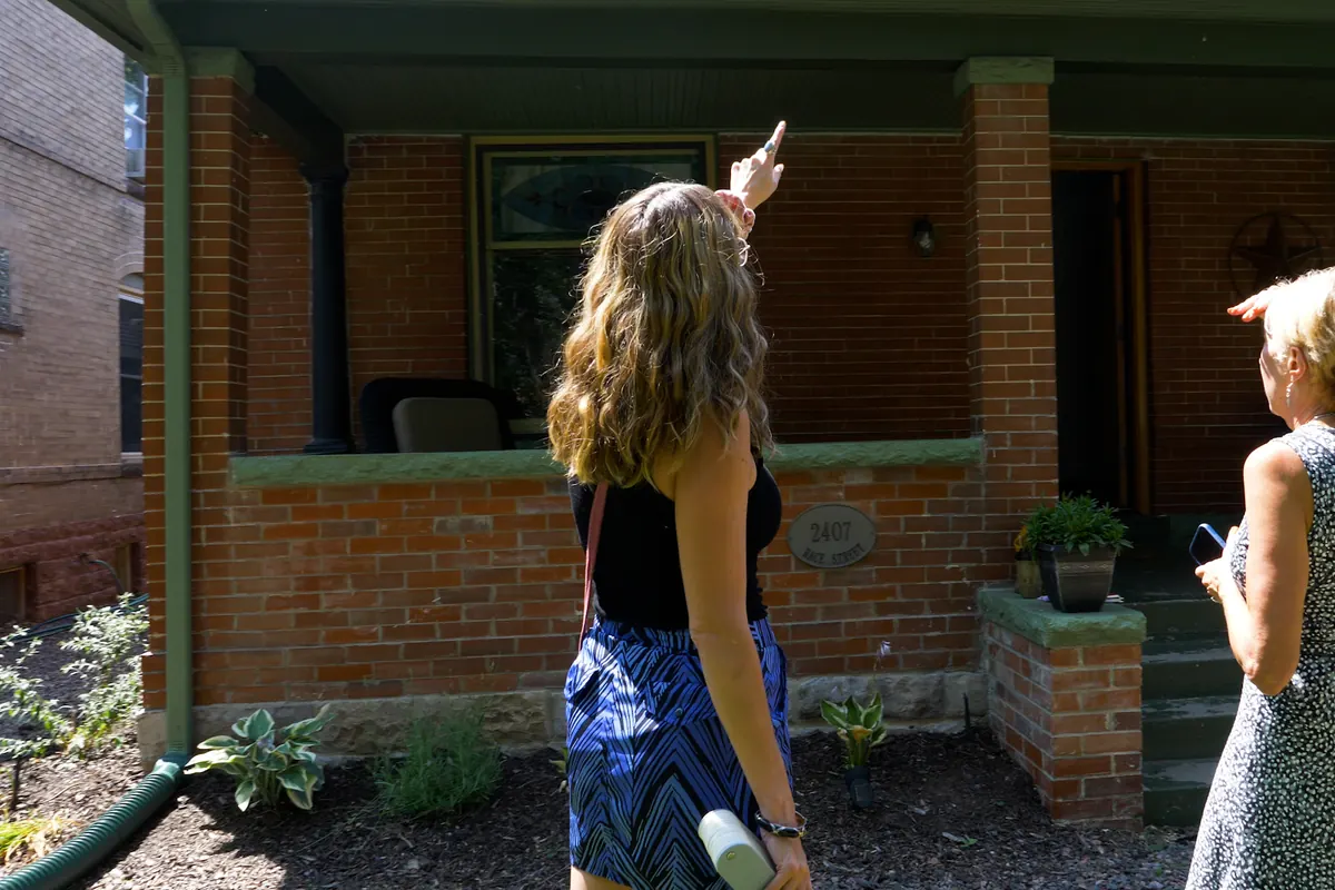 A Kind Home color consultant pointing out exterior trim details to a client on a brick porch